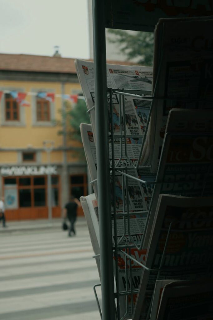 Newspaper stand on a bustling city street with pedestrians crossing outside the store.